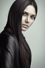 Closeup portrait of beautiful young brunette woman in a leather jacket. Long and straight brown hair. Natural makeup.