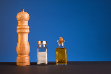 Obraz na płótnie Canvas Salt, pepper and olive oil, blue background.