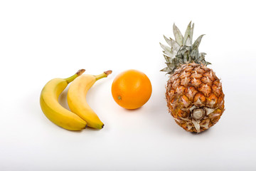 Bananas, oranges and pineapple on the table on a white backgroun