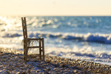lone wooden chair on the seashore at sunset and waves