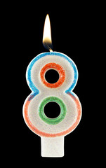 Burning birthday candle on black background, number 8