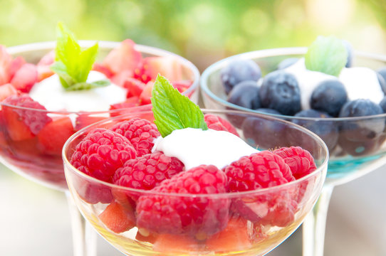 Berries dessert (raspberries, blueberries, strawberries) wth cream in glass bowls