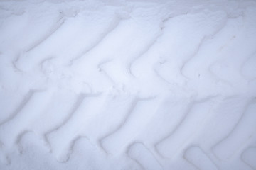 The trail from the tread of the car on the white snow.