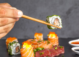 Hand with chopsticks holding sushi roll