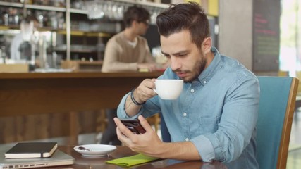 Hispanic Ethnicity Young Man using Mobile Phone at Cozy Coffee Shop. Shot on RED Cinema Camera in 4K (UHD).
