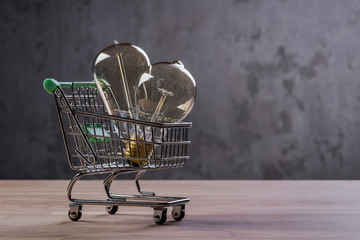 Shopping cart with vintage bulbs on wooden surface