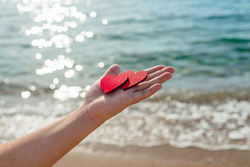 two red hearts on the palm of the girl on sea wave background