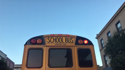 Following a school bus in the early morning in a small town as it stops to pick up children.	