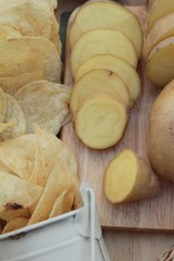 Crispy potato chips with salt and fresh potatoes.