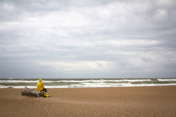 Men in yellow raincoat on the beach looking at storm.