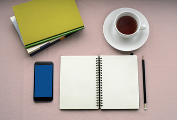 Fototapeta na wymiar Tea in white cup with Journal book and smartphone