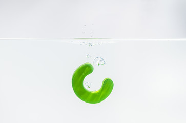 Fototapeta premium Green wooden alphabet C drop in the water with white background and selective focus