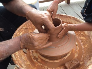 maestro artesano enseñando a un niño a trabajar el barro