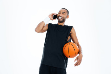 Obraz premium Laughing cheerful african basketball player talking on mobile phone