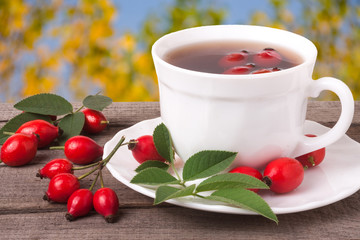 cup of tea rosehip berries on a dark wooden background