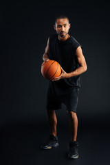 Fototapeta premium Full length portrait of a serious african sportsman playing basketball