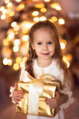Fototapeta na wymiar Caucasian girl with blond long hair Christmas gift, golden ligh