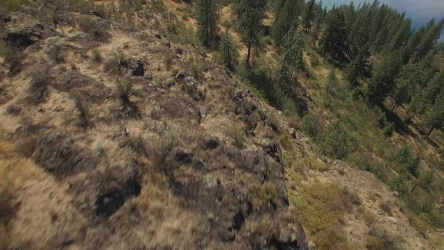 Drone Pilot Flying with Remote on Top of Rocky Mountain Cliff
