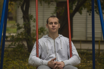 man sitting on a red swing thinking