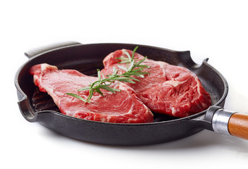 Raw beef steak on frying pan ready to cook, isolated on white