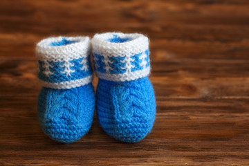 Fototapeta na wymiar Blue hand made crochet baby booties on wooden background, copyspace