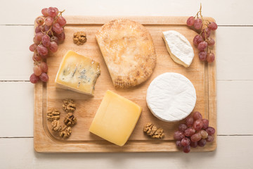 Cheese with grapes and walnuts on a wooden table 
