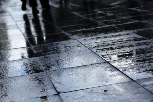 Silhouettes on wet road tiles