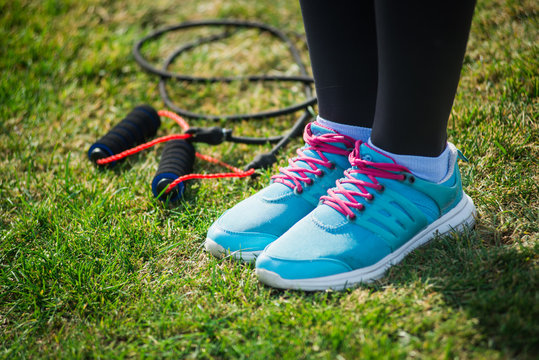 sneakers and variegated skipping rope on bright green grass background. Jumping rope on open air