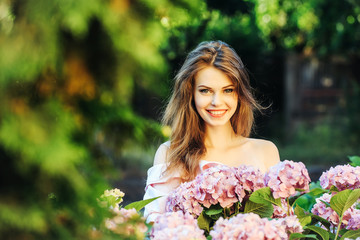 pretty smiling girl in hydrangea flowers