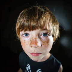 Emotive portrait of red-haired freckled boy, childhood concept