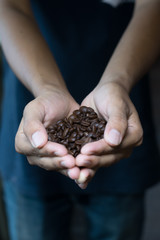 Man holding coffee beans in cupped hands, close-up
