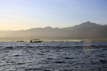Early morning sunrise at Lovina Beach in Bali, Indonesia with tradtional dolphin watching boats (Jukung) on the horizon