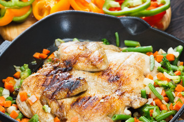 Whole grilled chicken on grill pan with vegetables and bell pepper