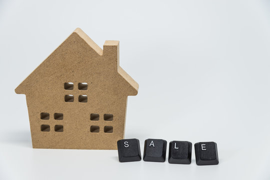 Wooden house toy and SALE word from keyboard with white background and selective focus