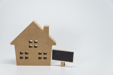 Wooden house toy and small black board with white background and selective focus