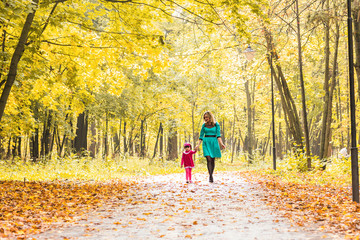 Obraz premium Happy mother and child daughter holding hands together in summer or autumn day.