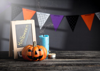 Halloween pumpkin head jack lantern and a chalkboard on wooden