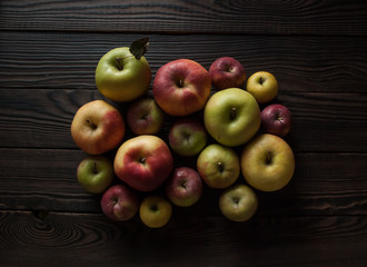 Colored apples of different sizes on wooden surface