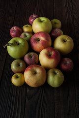 Colored apples of different sizes on a wooden surface