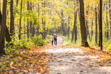 Obraz premium Happy young family walking down the road outside in autumn nature.