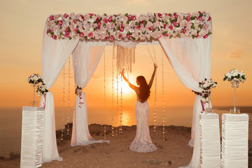 Sunset. bride silhouette. Wedding ceremony arch with flower arra