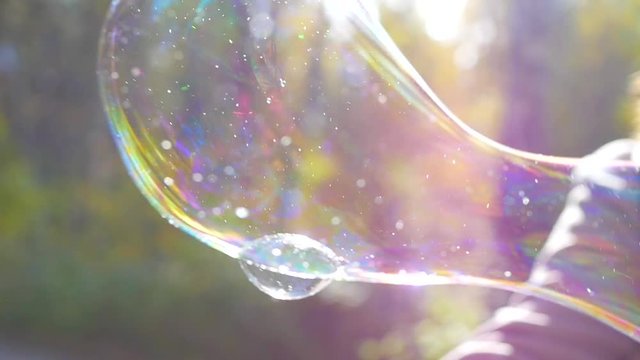 girl blowing large soap bubbles closeup in sunlight