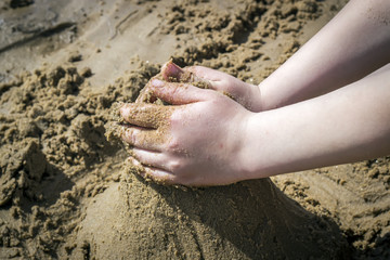 Child's hand build stronghold in salt white sand and.