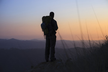 Silhouette man standing on rock and looking at view during sunset