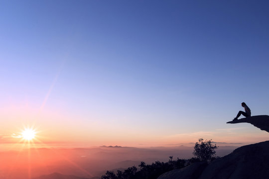 Woman sitting on Mt. Woodson against sky