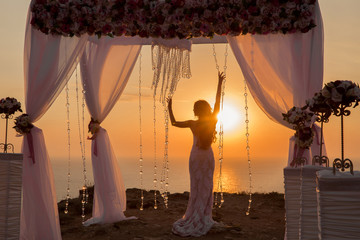 Sunset. bride silhouette. Wedding ceremony arch with flower arra