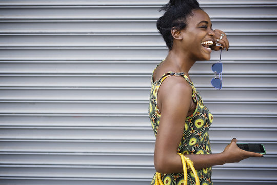 Woman laughing while standing against shutter