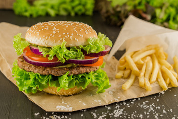 Fresh tasty burger and french fries on wooden table