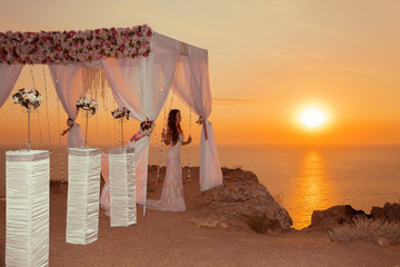 Sunset. bride silhouette. Wedding ceremony arch with flower arra