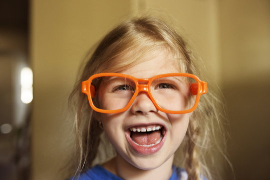 Happy girl with sunglasses frame at home